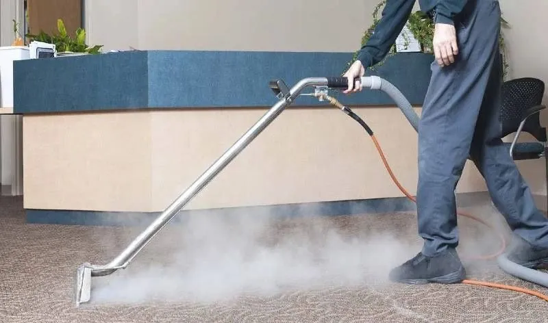 Technician steam cleaning a carpet
